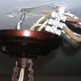 Podłączanie nowego żyrandola do starej instalacji: widoczne przewody i kostka elektryczna przy suficie.