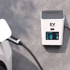 Ładowanie samochodu elektrycznego w domu. Stacja EV na ścianie, kabel podłączony do białego auta, bateria naładowana w 69%.