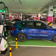Niebieski samochód elektryczny ładuje się przy stacji typu wallbox w podziemnym parkingu. To przyszłość transportu!