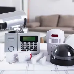 System alarmowy do monitoringu zewnętrznego domu jednorodzinnego przewodowego: kamera, panel sterowania, czujniki ruchu, dymu i klucze.