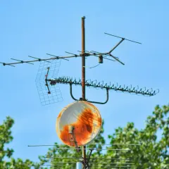Stara instalacja satelitarna z wieloma antenami i zardzewiałym talerzem, gotowa na odbiór sygnału.