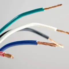 Kolorowy przewód elektryczny, z odsłoniętymi miedzianymi żyłami, tworzy tęczowy łuk na jasnym tle.