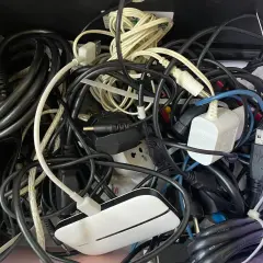 Plątanina starych kabli elektrycznych, zasilaczy i wtyczek tworzy chaotyczny obraz.
