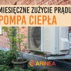 Pompa ciepła zamontowana na ścianie z cegły. Napis informuje o miesięcznym zużyciu prądu.