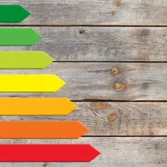 Kolorowe strzałki od A do G na drewnianym tle. Klasa energetyczna E jest pomarańczowa, wskazując na średnią efektywność.