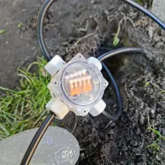 Przezroczysta puszka elektryczna do ziemi z pomarańczowymi diodami LED, podłączona do kabla.