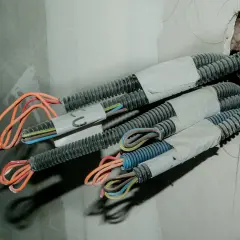 Przewody elektryczne w korytkach, przygotowane do dalszego układania. Widać kolorowe żyły wychodzące z osłon.