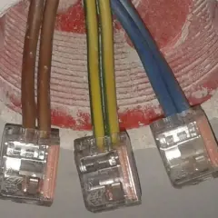 Żółto-zielony kabel oznacza uziemienie, kluczowy dla bezpieczeństwa instalacji elektrycznej. Widać go obok brązowych i niebieskich przewodów w puszkach.