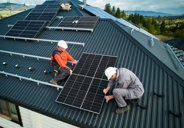 Dwóch mężczyzn montuje instalację fotowoltaiczną na dachu. Panele słoneczne zapewnią czystą energię.