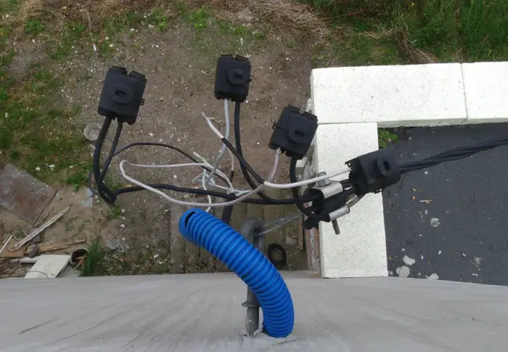 Widoczne połączenia kablowe, w tym niebieska peszla, wskazują na instalację elektryczną. To może być właśnie taki kabel od licznika do rozdzielni.