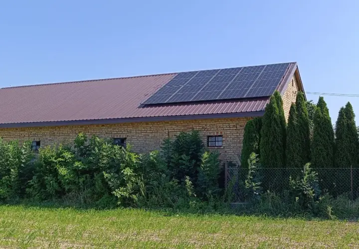 Panele fotowoltaiczne na dachu budynku gospodarczego. To rozwiązanie pozwala efektywnie zarządzać tym, jak wykorzystać nadmiar energii z fotowoltaiki, np. do magazynowania lub ogrzewania.