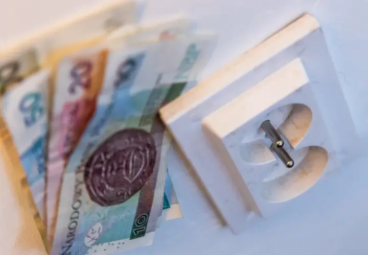 Pieniądze obok gniazdka elektrycznego. Dowiedz się, jak czytać rachunek za prąd PGE, by zrozumieć koszty.