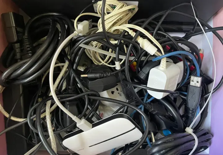 Plątanina starych kabli elektrycznych, zasilaczy i wtyczek tworzy chaotyczny obraz.