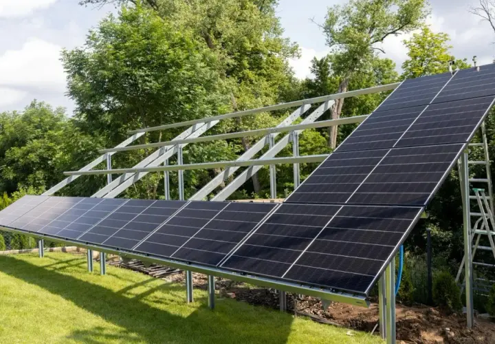 Montaż paneli fotowoltaicznych na solidnej konstrukcji. Instalacja w ogrodzie, gotowa do zbierania energii słonecznej.