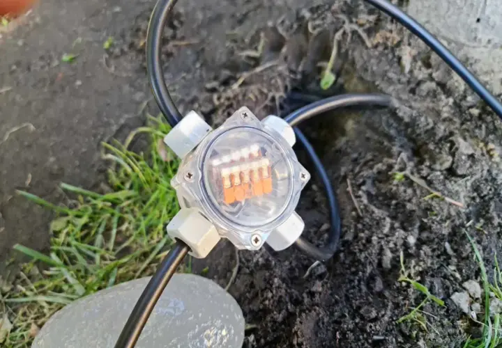 Przezroczysta puszka elektryczna do ziemi z pomarańczowymi diodami LED, podłączona do kabla.