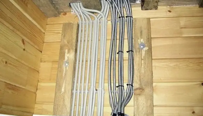 Przewody elektryczne w osłonach, starannie ułożone i przymocowane do drewnianych belek. Mocowanie przewodów elektrycznych do drewna wykonane estetycznie.