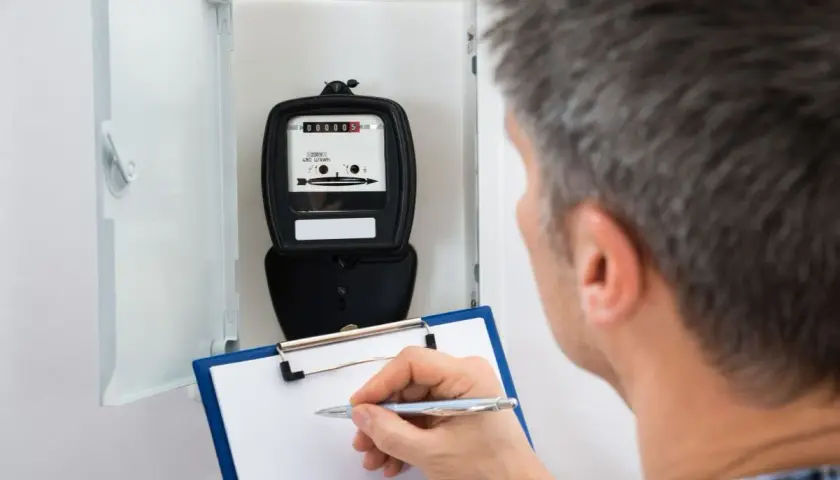 Mężczyzna notuje odczyt licznika energii elektrycznej, planując zwiększenie mocy przyłączeniowej w mieszkaniu.