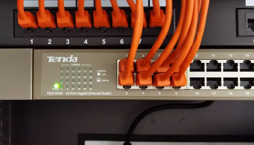 Pomarańczowe kable sieciowe podłączone do przełącznika Tenda TEG1024D, tworzące sieć LAN w domu.