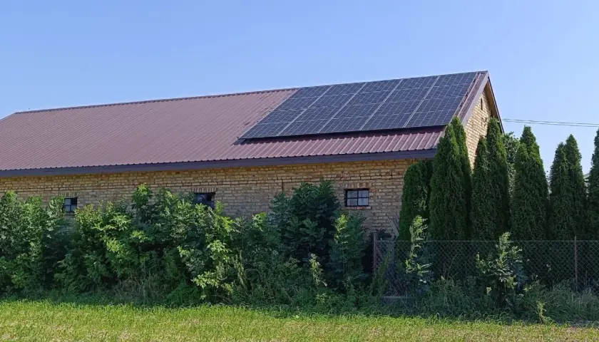 Panele fotowoltaiczne na dachu budynku gospodarczego. To rozwiązanie pozwala efektywnie zarządzać tym, jak wykorzystać nadmiar energii z fotowoltaiki, np. do magazynowania lub ogrzewania.
