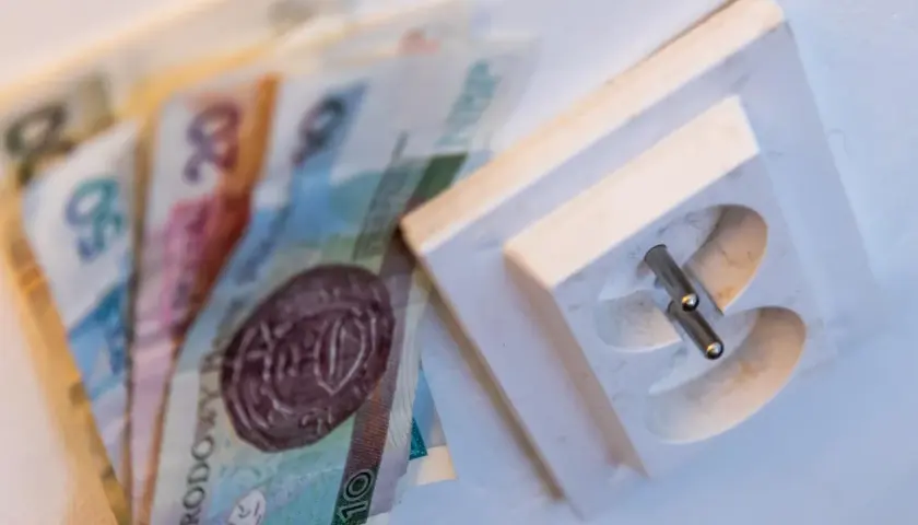 Pieniądze obok gniazdka elektrycznego. Dowiedz się, jak czytać rachunek za prąd PGE, by zrozumieć koszty.