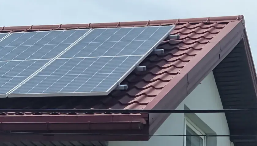 Panele fotowoltaiczne na dachu domu, zbierające energię słoneczną.