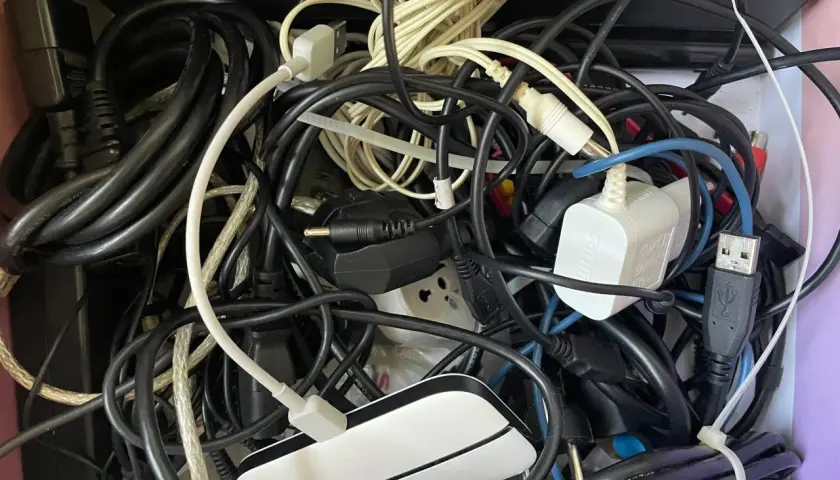 Plątanina starych kabli elektrycznych, zasilaczy i wtyczek tworzy chaotyczny obraz.