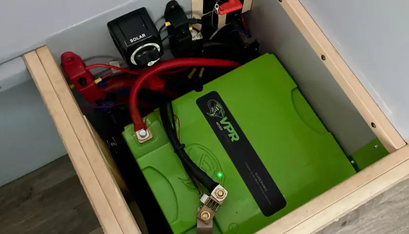System zasilania kampera: zielony akumulator litowo-jonowy VPR, wyłącznik solarny i odłącznik akumulatora.