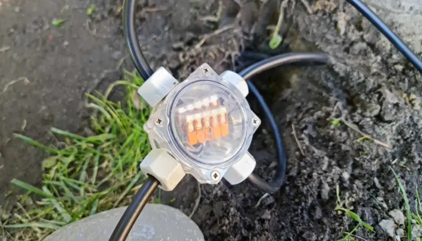 Przezroczysta puszka elektryczna do ziemi z pomarańczowymi diodami LED, podłączona do kabla.