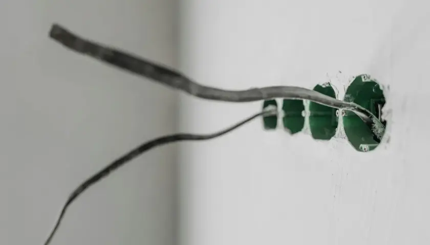 Przewody elektryczne wychodzą z zielonych puszek instalacyjnych w ścianie. Prąd w obu przewodach jest gotowy do podłączenia.