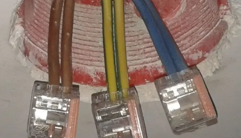 Żółto-zielony kabel oznacza uziemienie, kluczowy dla bezpieczeństwa instalacji elektrycznej. Widać go obok brązowych i niebieskich przewodów w puszkach.