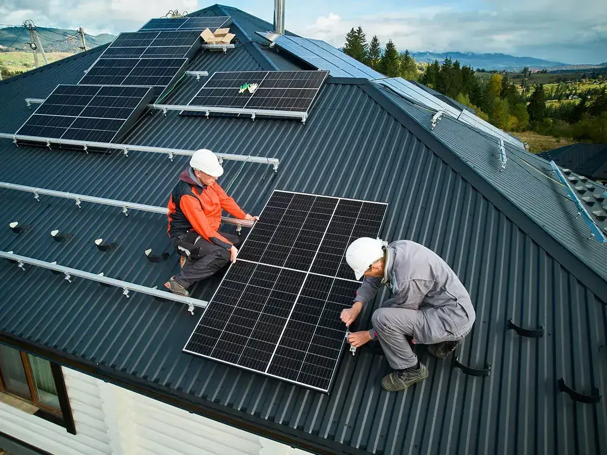 Dwóch mężczyzn montuje instalację fotowoltaiczną na dachu. Panele słoneczne zapewnią czystą energię.