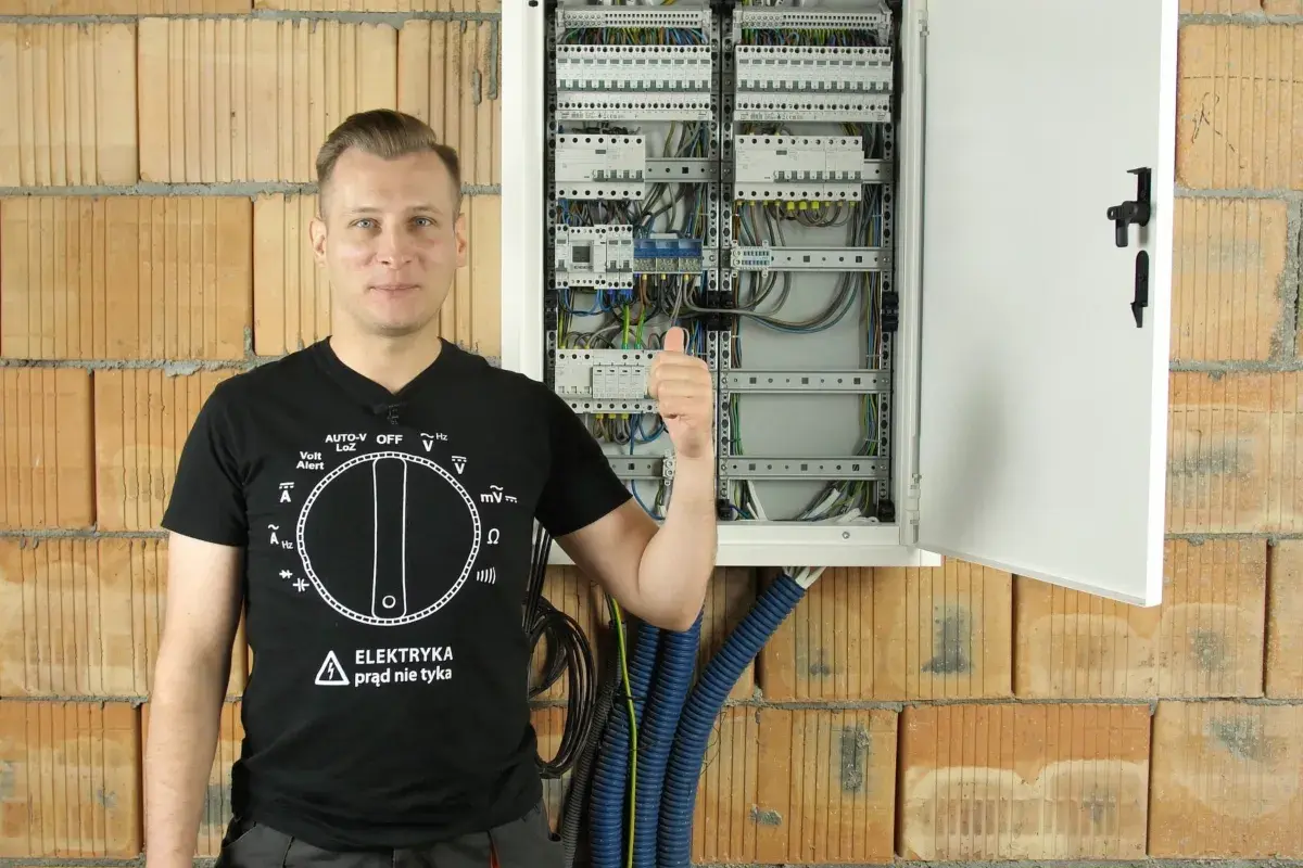 Elektryk pokazuje rozdzielnicę, odpowiadając na pytanie, ile różnicówek w domu jest bezpieczne.