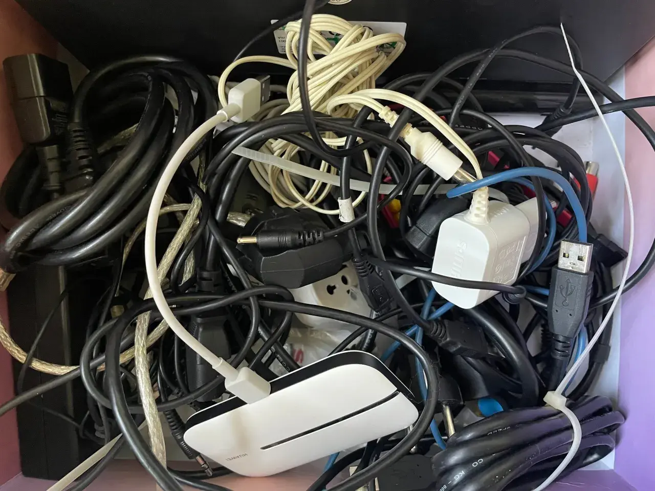 Plątanina starych kabli elektrycznych, zasilaczy i wtyczek tworzy chaotyczny obraz.