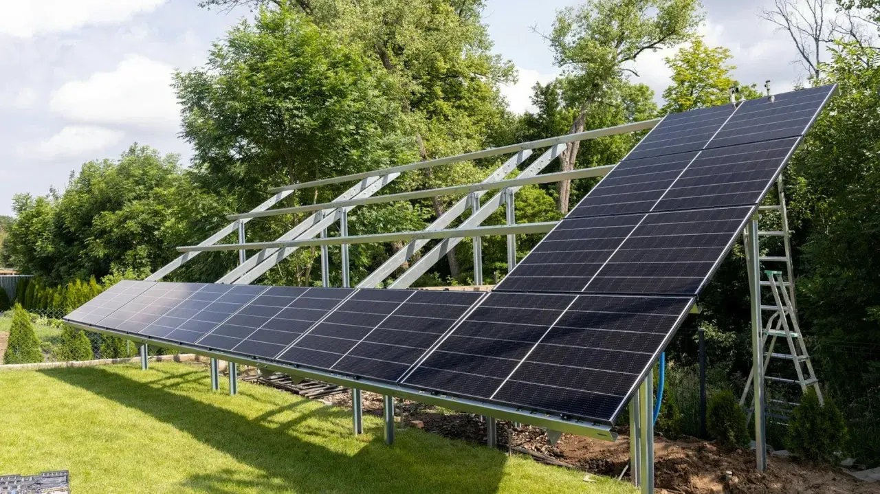 Montaż paneli fotowoltaicznych na solidnej konstrukcji. Instalacja w ogrodzie, gotowa do zbierania energii słonecznej.
