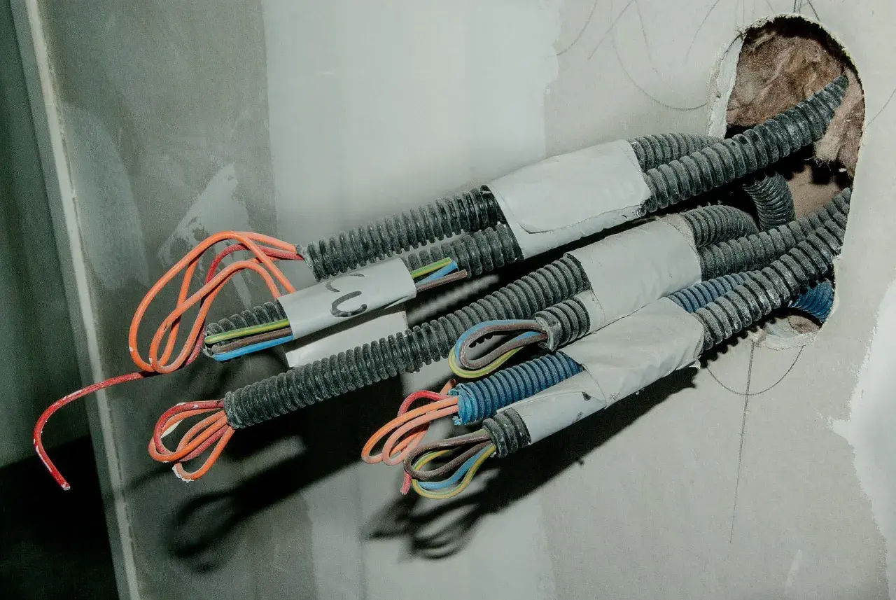 Przewody elektryczne w korytkach, przygotowane do dalszego układania. Widać kolorowe żyły wychodzące z osłon.