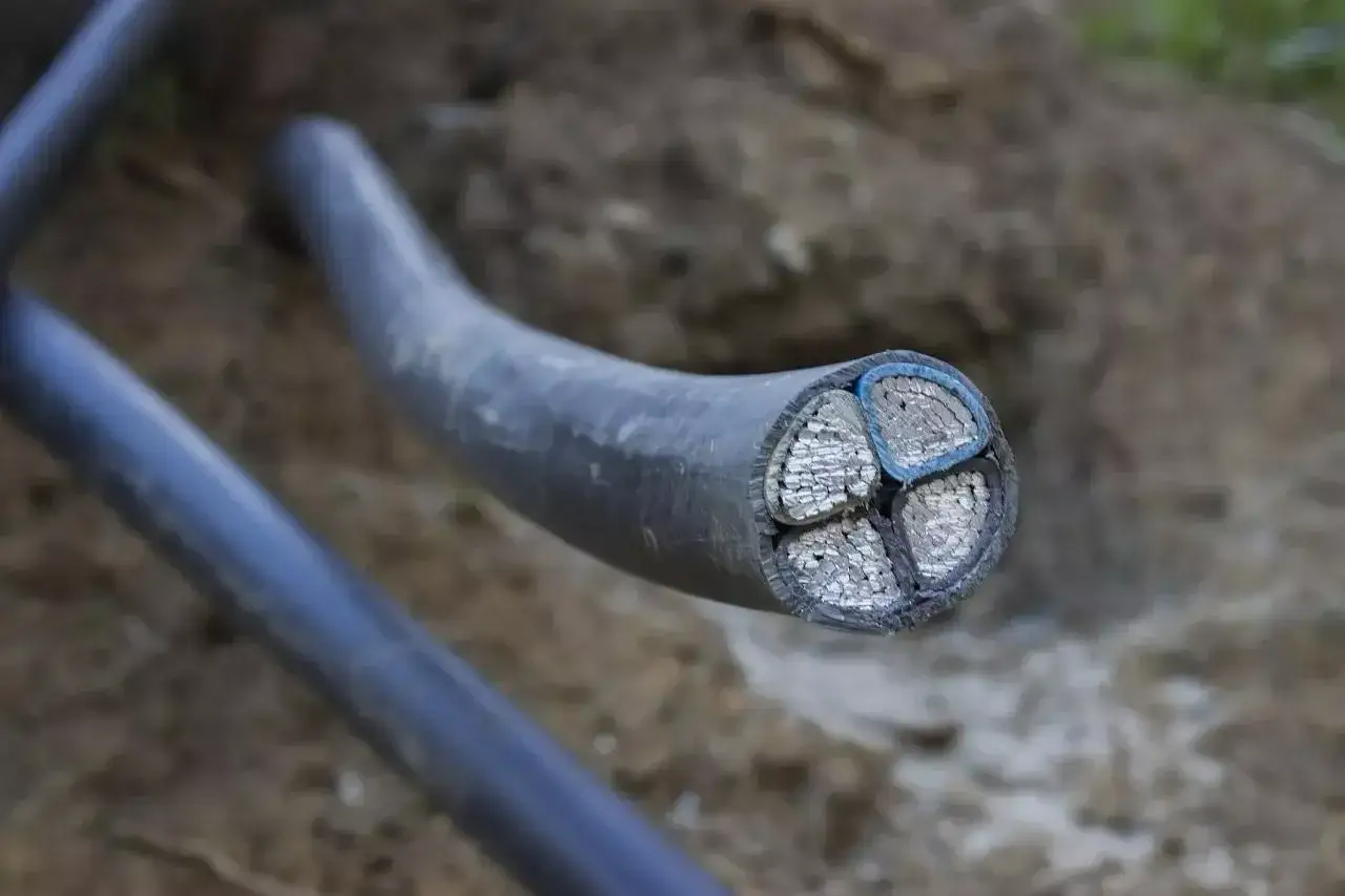 Przekrój kabla energetycznego z czterema żyłami. Widać różnicę między grubością żył a osłoną, która przypomina peszel.