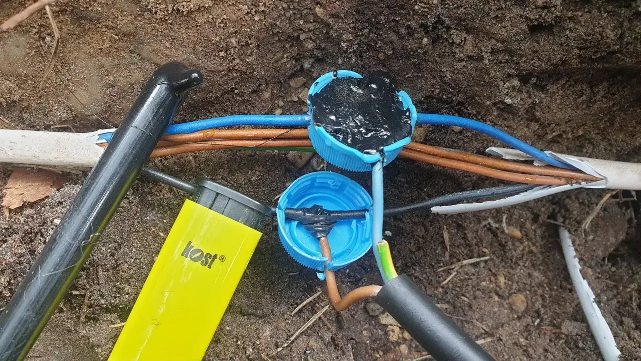 Jak zabezpieczyć przewody elektryczne przed wodą? Widać tu połączenie kabli zalane masą uszczelniającą w niebieskich nakrętkach, co chroni je przed wilgocią.