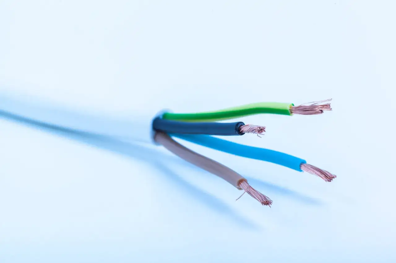 Kabel ż&oacute;łto-zielony oznacza uziemienie, chroniąc przed porażeniem. Widać go obok niebieskiego i brązowego przewodu.