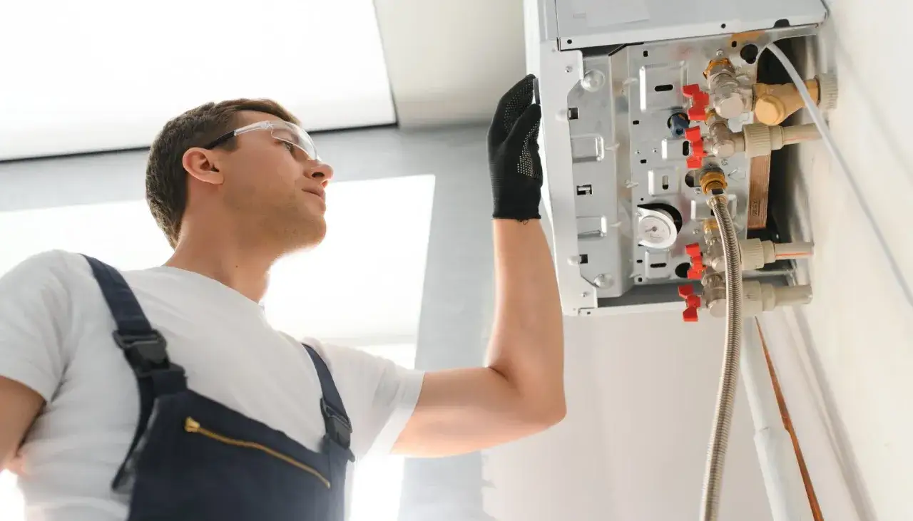 Technik w okularach ochronnych sprawdza pompę ciepła, diagnozując awarię przepływu wody.