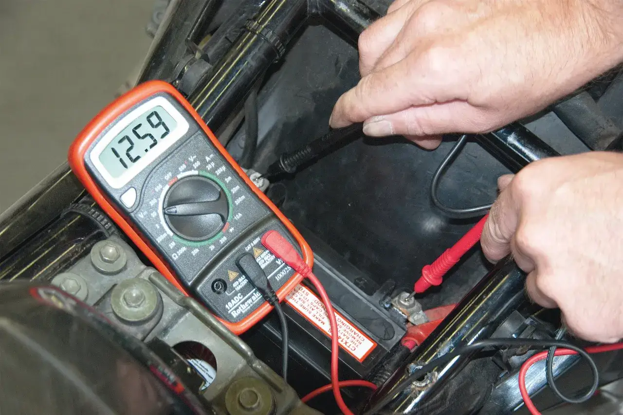 Pomiar napięcia akumulatora multimetrem. 12.59V to prawidłowe napięcie spoczynkowe, brak zwarcia do plusa.